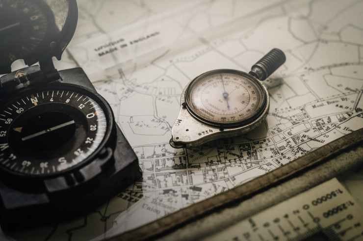 shallow focus photography of black and silver compasses on top of map